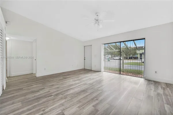 a view of an empty room with wooden floor and a window