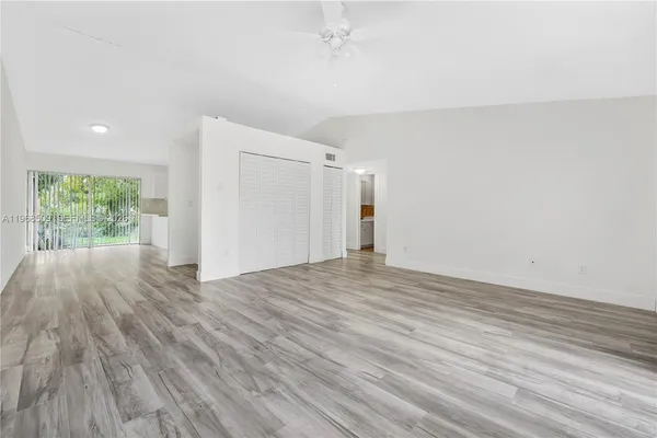 a view of an empty room with wooden floor and a window