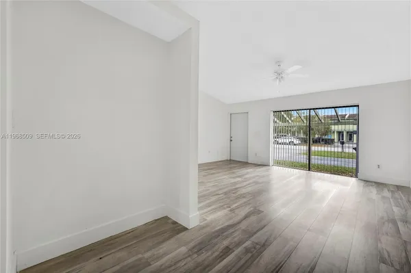 a view of an empty room with wooden floor and a window