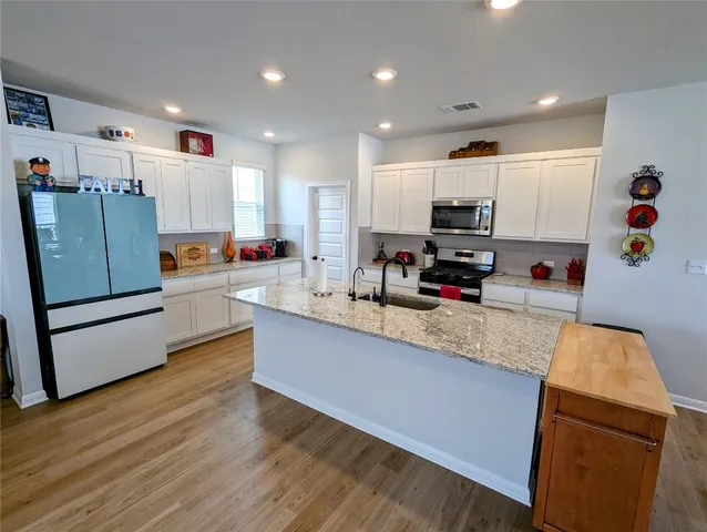 a kitchen with stainless steel appliances granite countertop a stove top oven a sink dishwasher and a microwave with wooden floor