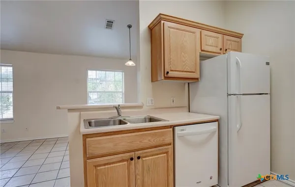 a kitchen with a sink a refrigerator and cabinets