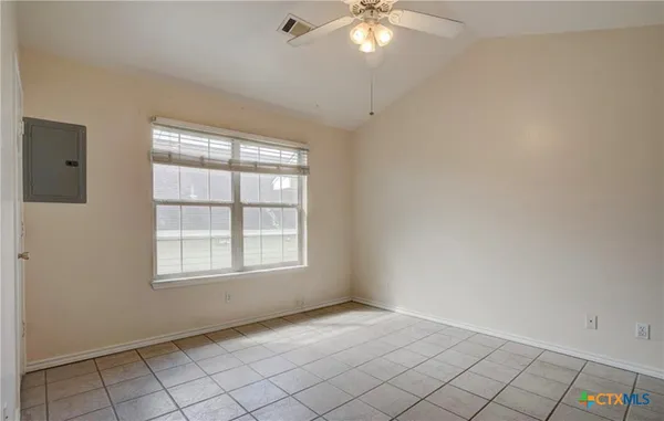 an empty room with chandelier fan and window
