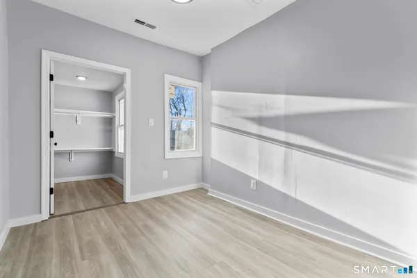 a view of an empty room with window and wooden floor