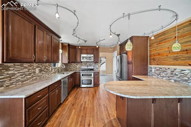 a kitchen with stainless steel appliances kitchen island granite countertop a stove a sink dishwasher and a refrigerator with wooden cabinets