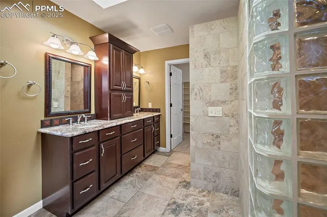 a bathroom with a granite countertop double vanity sink and a mirror