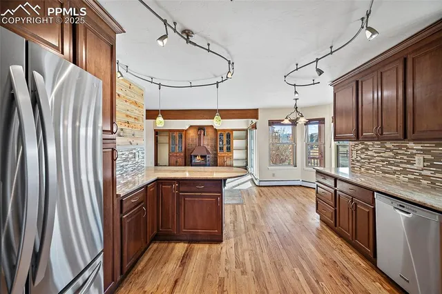 a kitchen with stainless steel appliances granite countertop a refrigerator a sink and wooden floors
