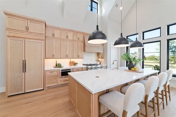 a kitchen with stainless steel appliances granite countertop a stove a refrigerator a sink a dining table and chairs with wooden floor