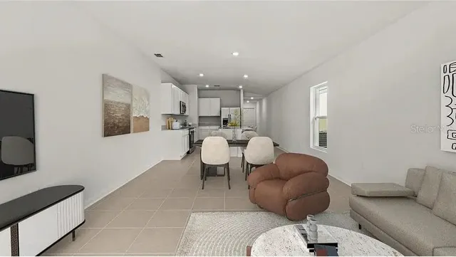 a living room with furniture kitchen view and a wooden floor