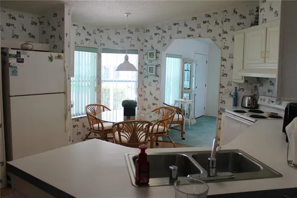 a living room with furniture a large window with white kitchen