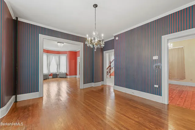 a view of a big room with wooden floor and chandelier