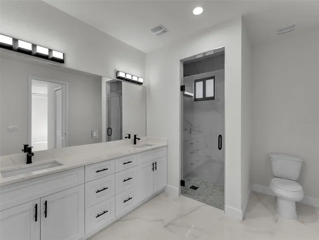 a bathroom with a double vanity sink toilet and shower