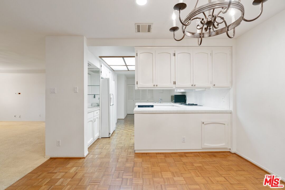 11687 Bellagio Road, Unit 5 Los Angeles, CA 90049 - Photo 11 of 31 a kitchen with stainless steel appliances a white cabinets and a chandelier