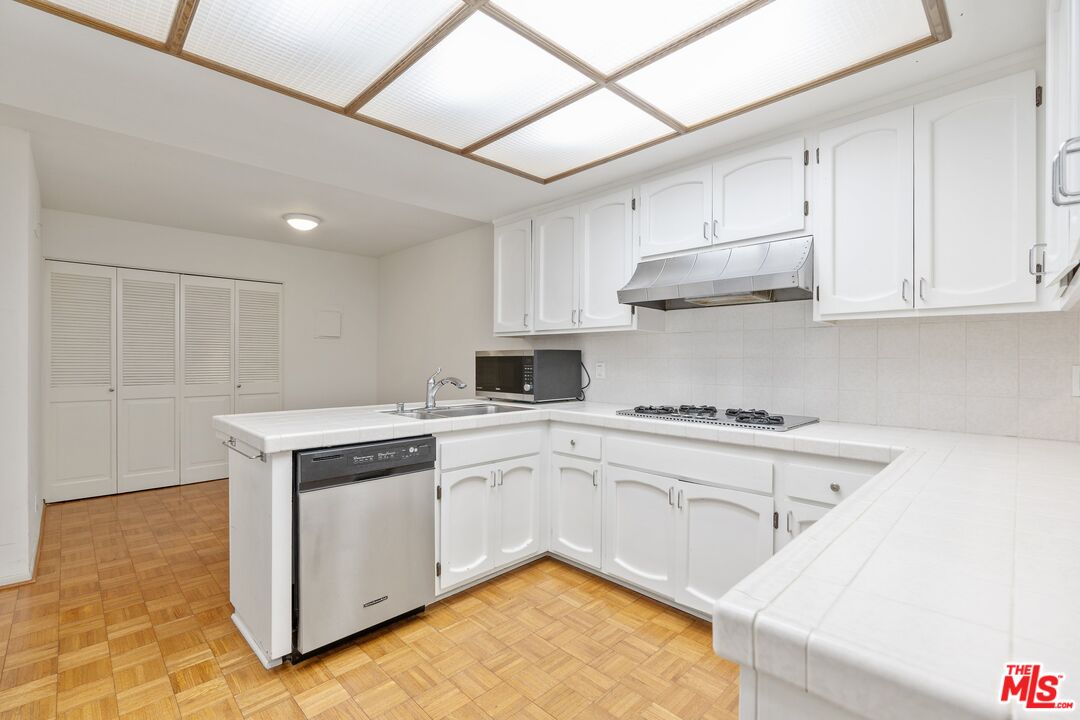 11687 Bellagio Road, Unit 5 Los Angeles, CA 90049 - Photo 12 of 31 a kitchen with a stove sink and cabinets