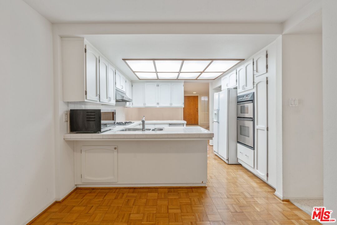 11687 Bellagio Road, Unit 5 Los Angeles, CA 90049 - Photo 15 of 31 a view with kitchen island a sink a refrigerator and window