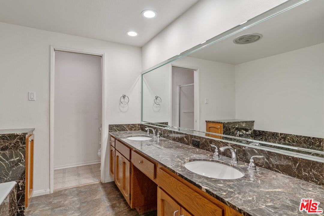 11687 Bellagio Road, Unit 5 Los Angeles, CA 90049 - Photo 18 of 31 a bathroom with a granite countertop double vanity sink and a mirror