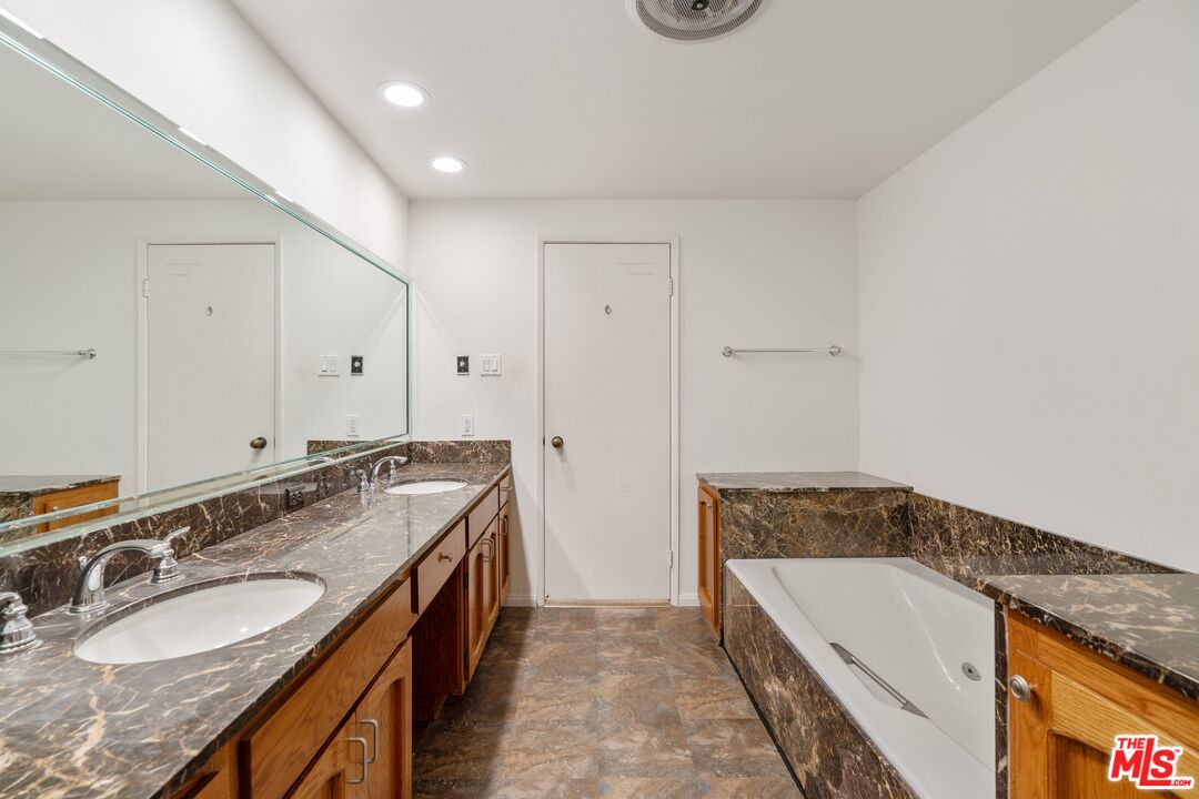 11687 Bellagio Road, Unit 5 Los Angeles, CA 90049 - Photo 19 of 31 a spacious bathroom with a granite countertop tub sink and mirror