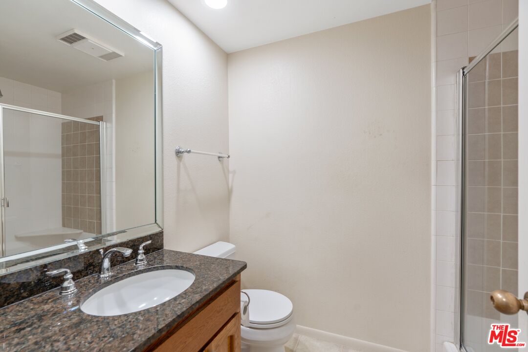 11687 Bellagio Road, Unit 5 Los Angeles, CA 90049 - Photo 24 of 31 a bathroom with a granite countertop sink toilet a mirror and shower