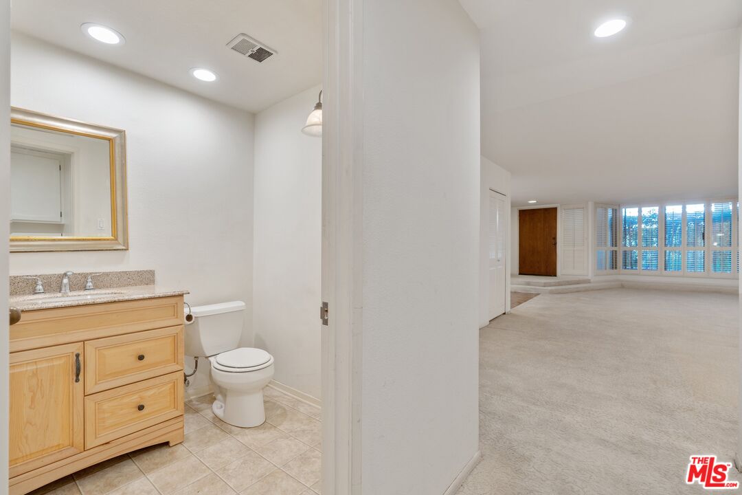 11687 Bellagio Road, Unit 5 Los Angeles, CA 90049 - Photo 25 of 31 a spacious bathroom with a toilet sink and mirror