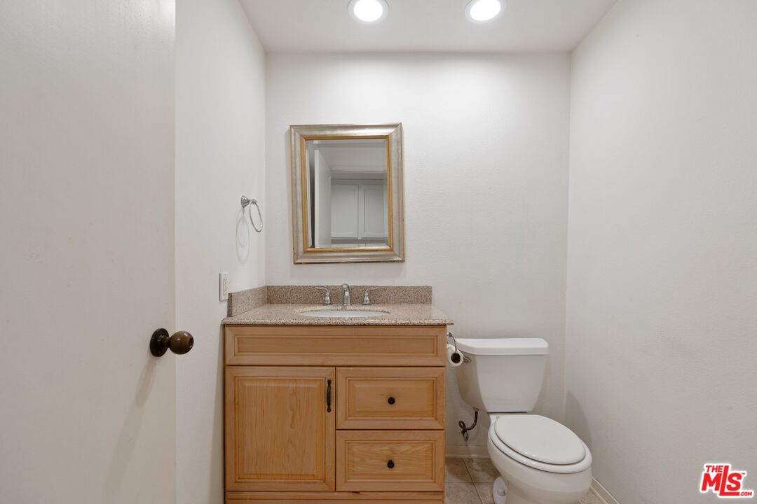 11687 Bellagio Road, Unit 5 Los Angeles, CA 90049 - Photo 26 of 31 a bathroom with a granite countertop toilet sink and mirror