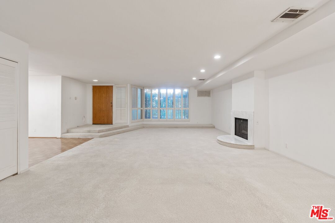 11687 Bellagio Road, Unit 5 Los Angeles, CA 90049 - Photo 8 of 31 a view of an empty room with a fireplace and a window