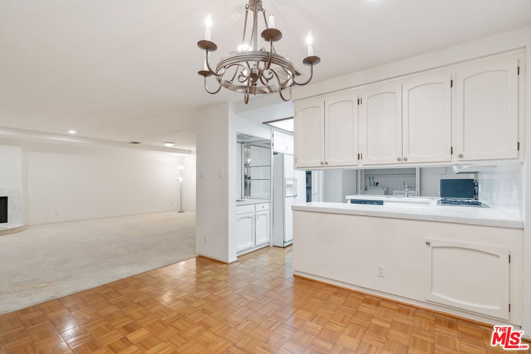 11687 Bellagio Road, Unit 5 Los Angeles, CA 90049 - Photo 10 of 31 a kitchen with kitchen island white cabinets and refrigerator