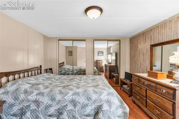 a spacious bedroom with a bed and a large mirror on the dresser