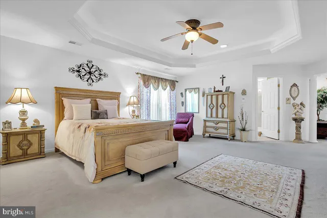 a spacious bedroom with a bed a couch and a chandelier