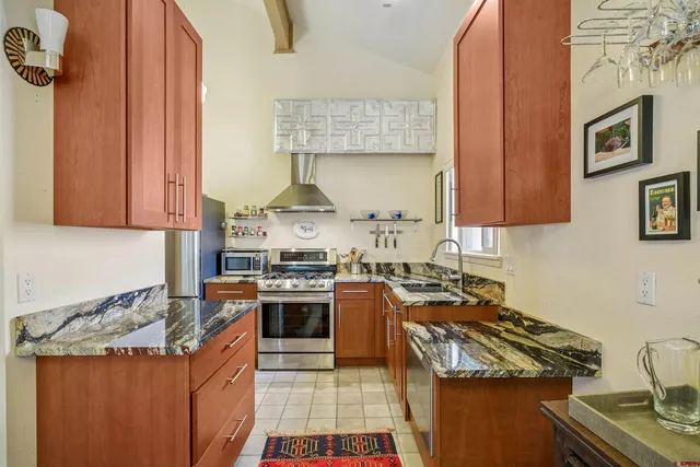 a kitchen with stainless steel appliances granite countertop a stove top oven a sink dishwasher and cabinets with wooden floor