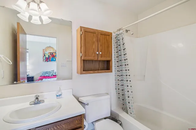 a bathroom with a sink a toilet a shower curtain and a mirror