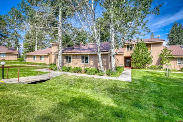 a view of a house with a yard deck and a large tree
