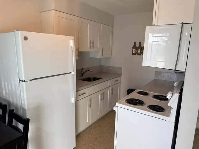 a white refrigerator freezer and a stove sitting inside of a kitchen