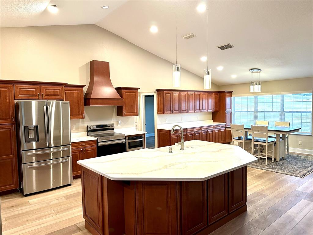11735 Southeast 174th Loop Summerfield, FL 34491 - Photo 7 of 19 a kitchen with stainless steel appliances kitchen island granite countertop a sink and a refrigerator