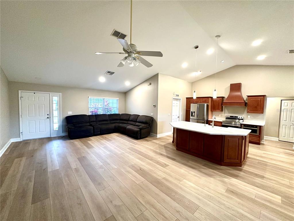11735 Southeast 174th Loop Summerfield, FL 34491 - Photo 10 of 19 a large room with kitchen island a sink dishwasher a dining table and chairs with wooden floor