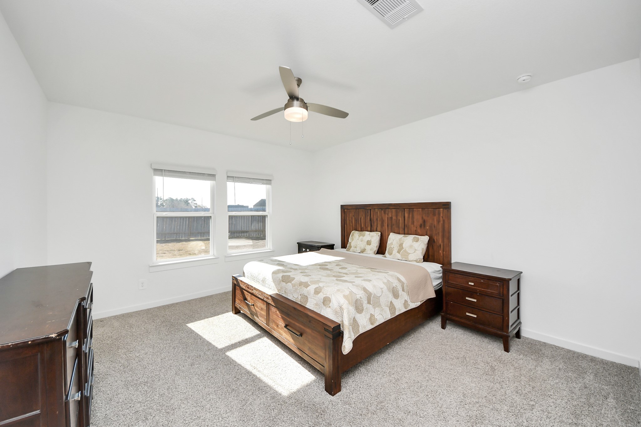 28603 Crowley Court Katy, TX 77494 - Photo 17 of 50 This spacious primary bedroom features two large windows for natural light, neutral walls, carpeted flooring, and a ceiling fan. The view of the backyard offering a private and comfortable retreat.