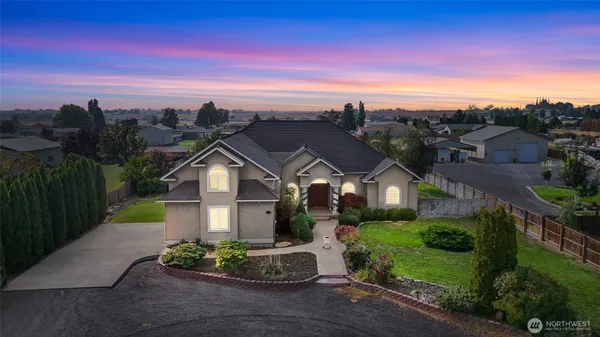 a view of a big house with a big yard plants and large trees