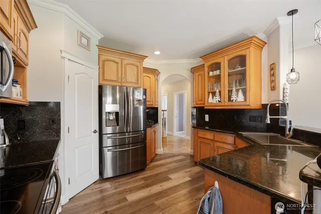 a kitchen with stainless steel appliances granite countertop a refrigerator a stove and a sink with wooden floor