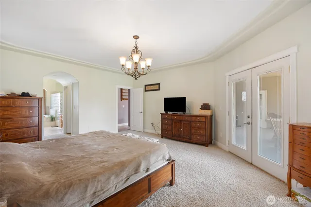 a spacious bedroom with a bed and a chandelier