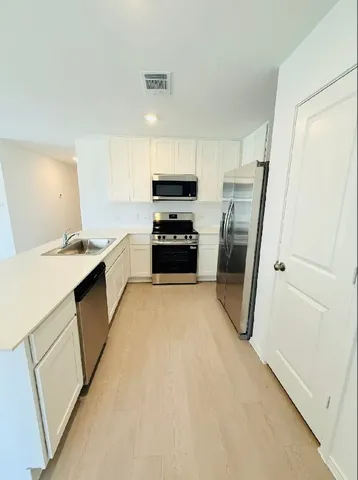 a kitchen with a refrigerator a stove top oven and white cabinets