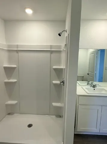a bathroom with a shower a sink and toilet