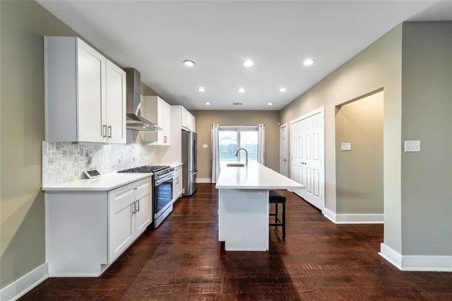 a large kitchen with granite countertop a large counter top a sink stainless steel appliances and cabinets