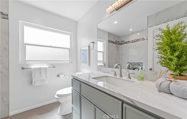 a bathroom with a granite countertop sink mirror vanity and toilet