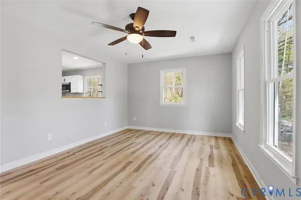a view of empty room with wooden floor and fan