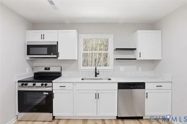 a kitchen with white cabinets stainless steel appliances and sink