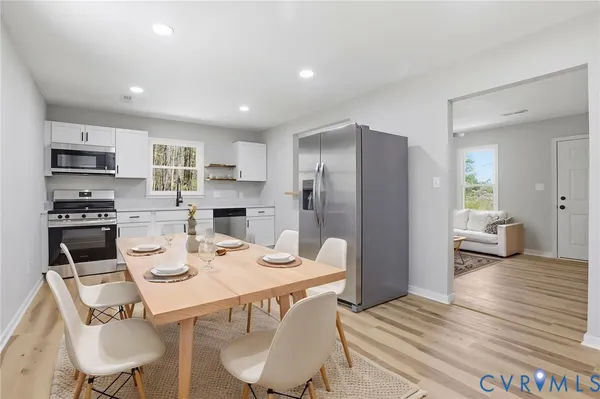 a kitchen with a refrigerator a stove and a dining table with wooden floor