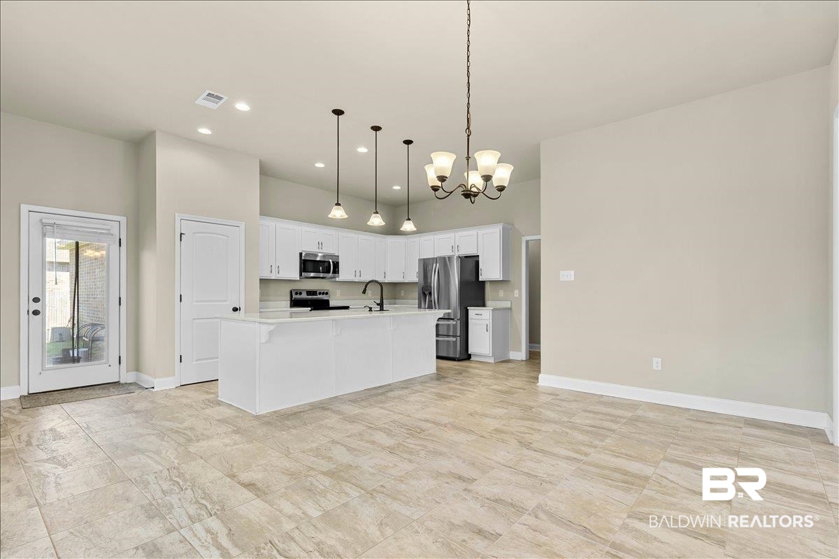 1112 Stella Road Foley, AL 36535 - Photo 7 of 33 Kitchen with white cabinetry, a chandelier, stainless steel appliances, a center island with sink, and a high ceiling