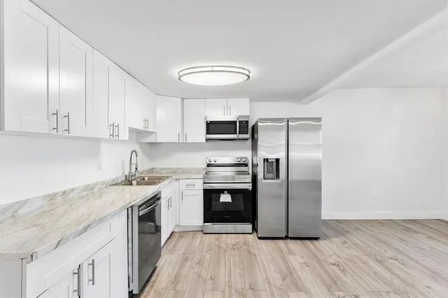 a kitchen with stainless steel appliances granite countertop a stove a sink and a refrigerator