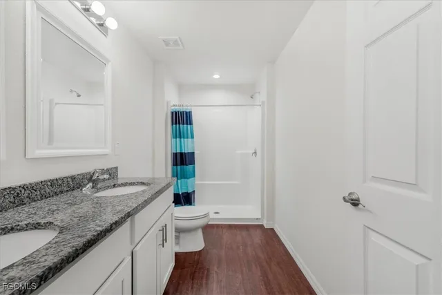 a bathroom with a granite countertop sink a toilet and shower