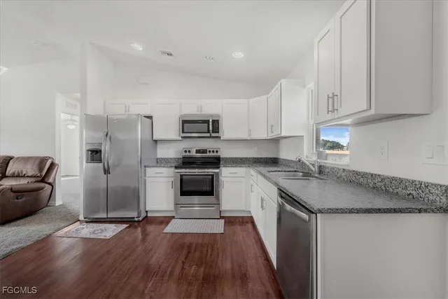 a kitchen with kitchen island granite countertop a sink cabinets and stainless steel appliances