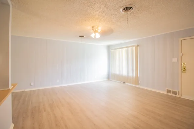 a view of an empty room with wooden floor and a window