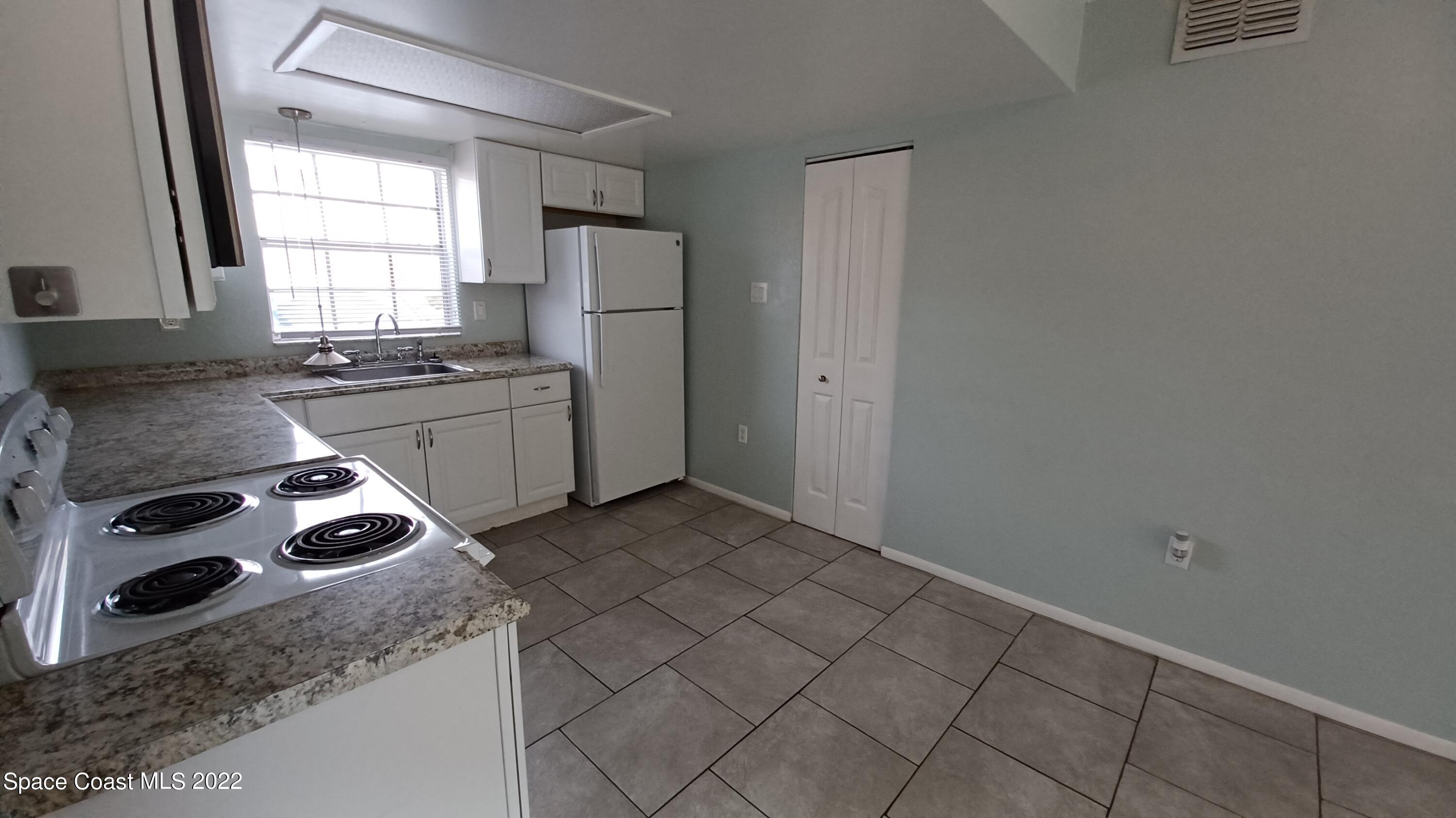 181 Ulster Lane Melbourne, FL 32935 - Photo 8 of 29 a kitchen with granite countertop cabinets a sink a window and stainless steel appliances